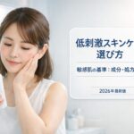 敏感肌の女性がスキンケアボトルの成分表示を確認しながら頬に触れている様子｜低刺激スキンケアの選び方ガイド2026年最新版